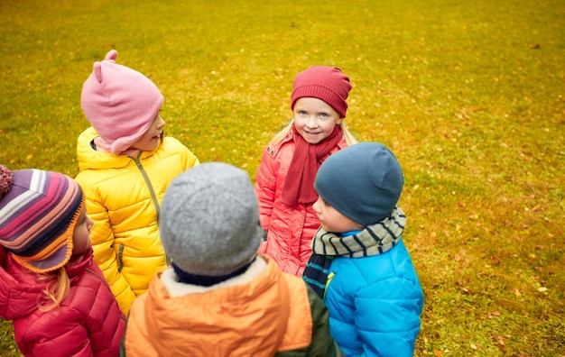 childhood, leisure, friendship and people concept - group of happy children standing in circle in autumn park