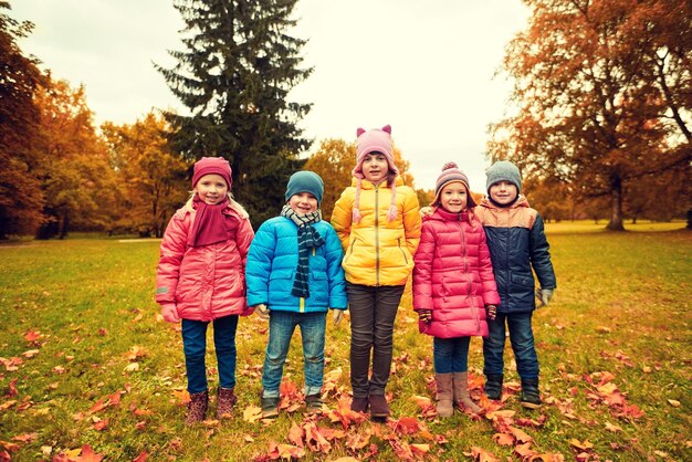 Childhood, leisure, friendship and people concept - group of happy kids in autumn park