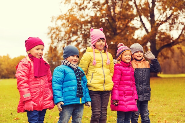 childhood, leisure, friendship and people concept - group of happy kids in autumn park