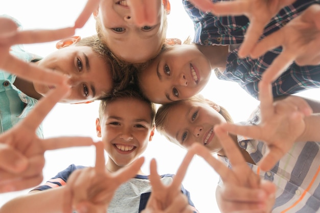 Foto concetto di infanzia, tempo libero, amicizia e persone - gruppo di bambini felici sorridenti che mostrano il segno v in cerchio