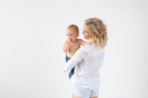 Childhood, motherhood and family concept - Portrait happy mother holds her baby on white background