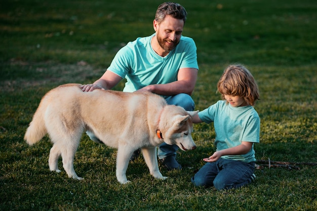 Childhood and parenthood kids concept happy father and son playing with pet dog outdoor child with h