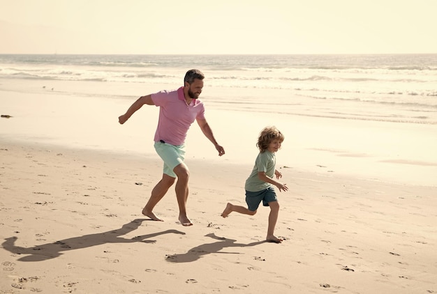 夏のビーチで走っている子供と子育ての父と息子は週末と休暇を旅行します