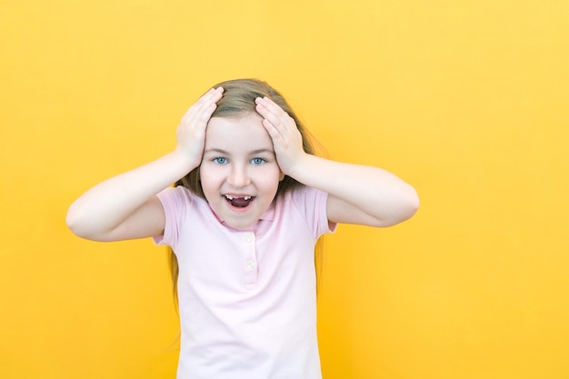 Childhood and people concept surprised or frightened little girl screaming on yellow background