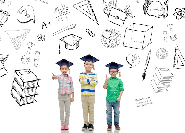 детство, школа, образование, знания и концепция людей - счастливые дети в холостяцких шляпах или шапочках и очках над каракулями