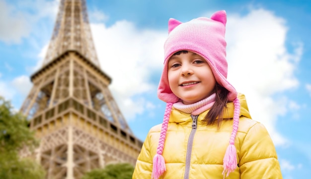 childhood, tourism, travel, vacation and people concept - happy beautiful little girl over eiffel tower in paris background