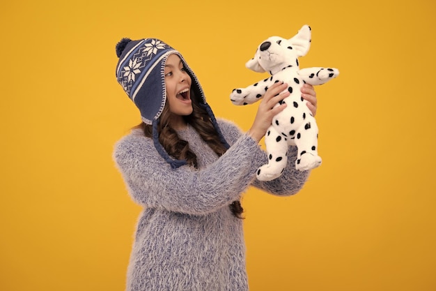 Childhood toys and kids cute teen girl in winter hat cuddling fluffy toy excited teenager girl