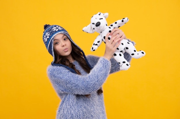 Childhood toys and kids Cute teen girl in winter hat cuddling fluffy toy Funny face