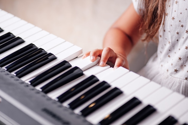 Childish hand of a girl learning music on an electronic synthesizer