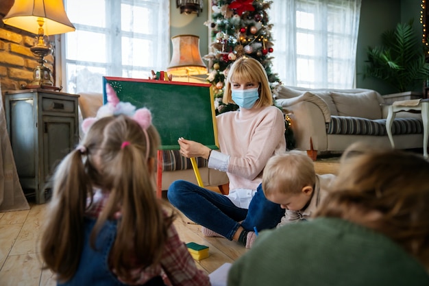 Няня и дети с маской для лица из-за Covid-19 и коронавируса в дошкольных учреждениях