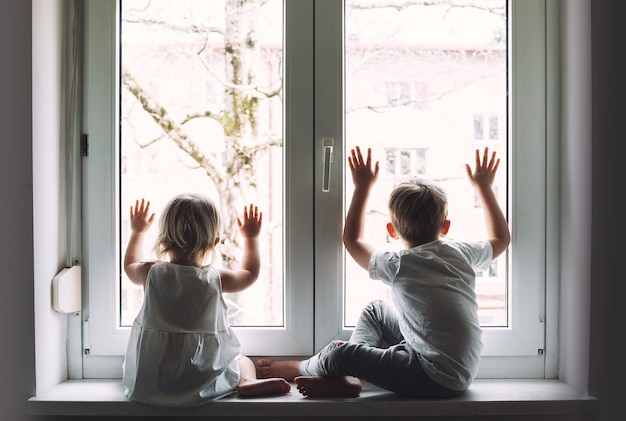 子供たちは自宅で検疫を行っており、窓の外を見る検疫パンデミックコロナウイルスcovid19