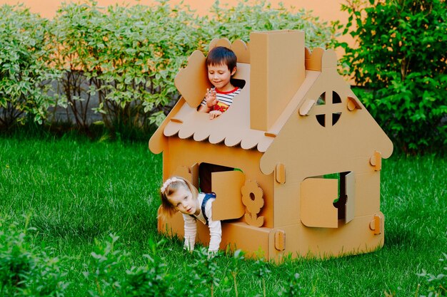 写真 子供たちは紙板の子供の家で遊んでいます子供は屋外で楽しんでいます