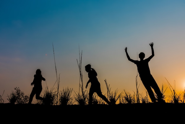 The children are running on the meadow at sunset.