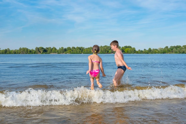 아이들은 해변 시즌이 열리는 화창한 날 물 위를 달리고 있습니다.