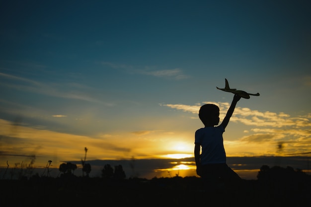 Дети на фоне солнца с самолетом в руке