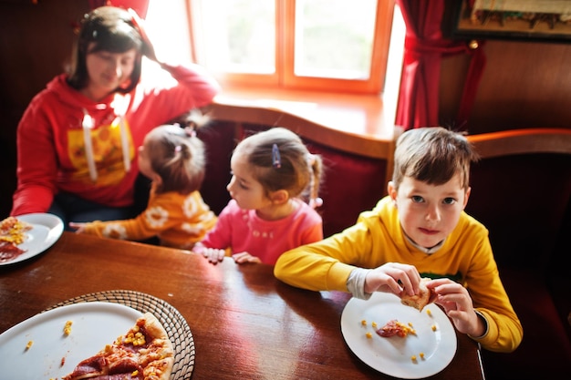 Children on birthdays sitting at the table and eating pizza