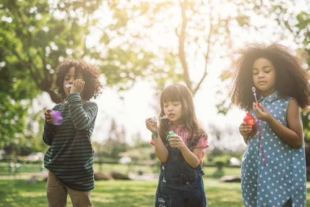 Foto bambini che soffiano bolle nel parco