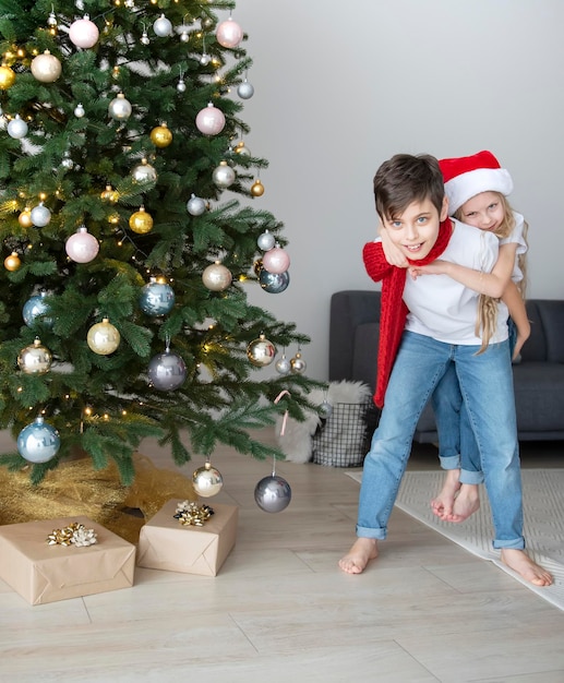 男の子と女の子がクリスマスツリーの近くで遊んでいる子供たち