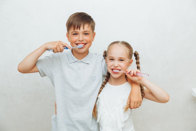 I bambini un ragazzo e una ragazza si lavano i denti e ridono isolati su uno sfondo bianco igiene dentale pediatrica e pulizia dei denti