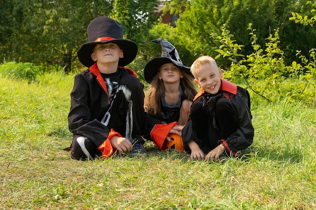 Children boy and girl in carnival costumes of witches and skeleton on street are enjoying Halloween holiday witch39s hat Happy kids vampire jack o lantern Autumn October All Saints39 Day