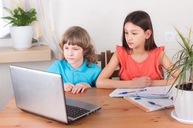 Children boy and girl on distance education, homeschooling and doing homework. e-learning at home, web lesson concept