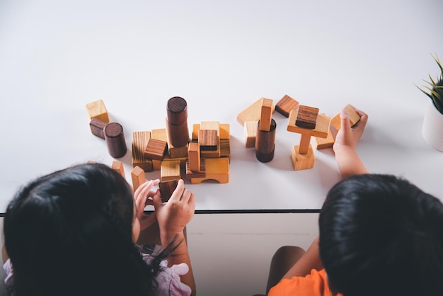 Children boy and girl playing with constructor wooden block building