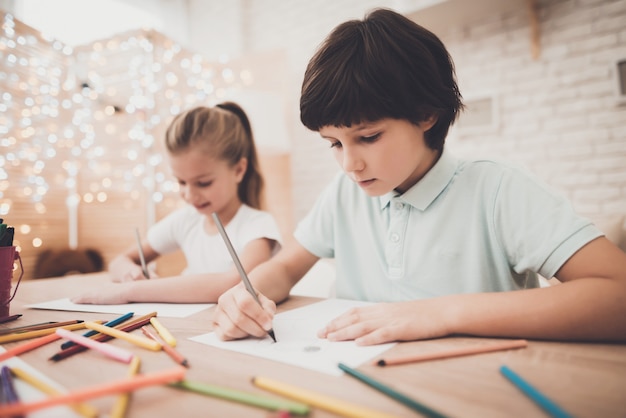 子供男の子と女の子の兄弟は鉛筆で描く