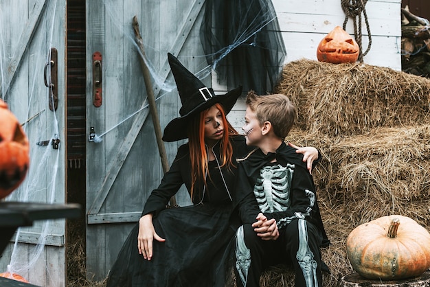 Children a boy in a skeleton costume and a girl in a witch costume having fun at a Halloween party on the decorated porch