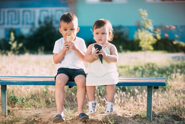 Bambini, fratello e sorella in panchina a mangiare il gelato è molto divertente e carino