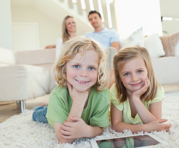 Children on the carpet with tablet and parents behind them