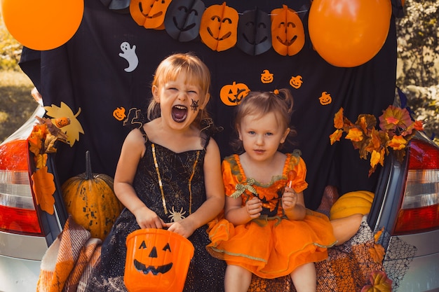 Children celebrating halloween in trunk of car