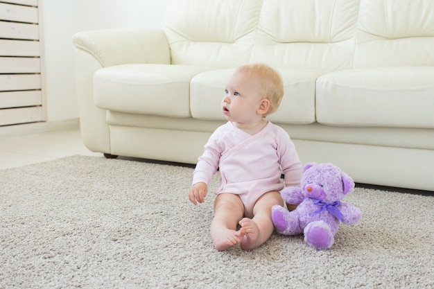 Children and childhood concept - Little baby girl sitting on the floor