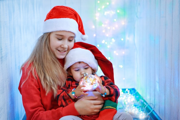 クリスマスツリーのおもちゃでクリスマス衣装を着た子供たち。新年、仮面舞踏会、休日、装飾の概念