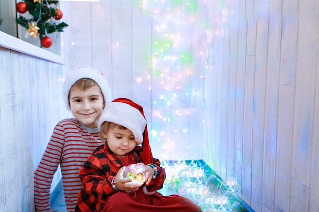 Bambini in costumi natalizi con un giocattolo dell'albero di natale. concetto di nuovo anno, travestimento, vacanze, decorazioni