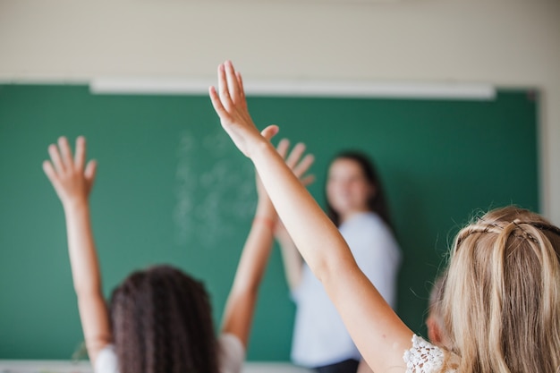 Photo children in classroom raising hands