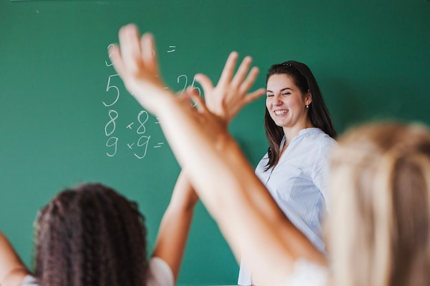 Photo children in classroom raising hands