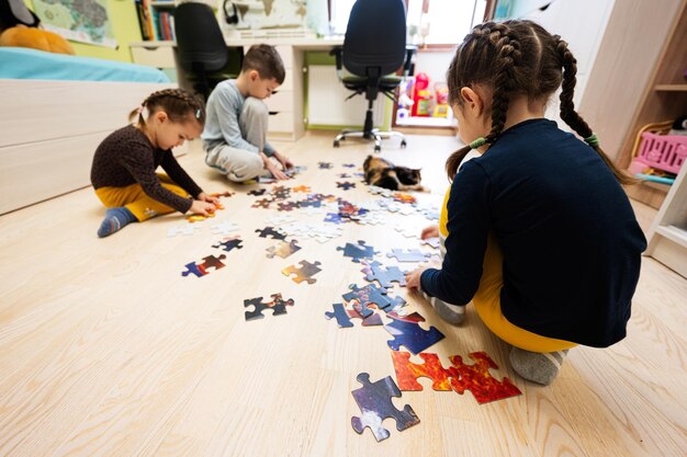 Children connecting jigsaw puzzle pieces in a kids room on floor at home Fun family activity leisure