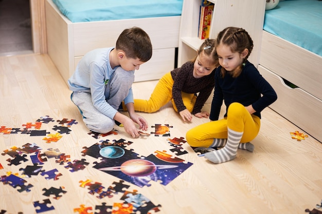 Children connecting jigsaw puzzle pieces in a kids room on floor at home Fun family activity leisure