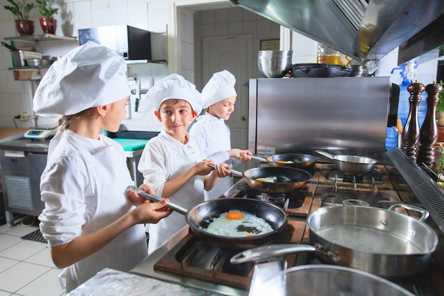 Bambini che cucinano il pranzo nella cucina di un ristorante.