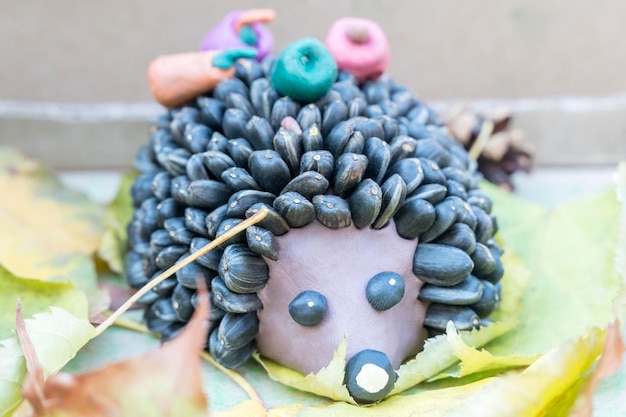Children crafts - hedgehog from plasticine and seeds instead of needles on autumn leaves