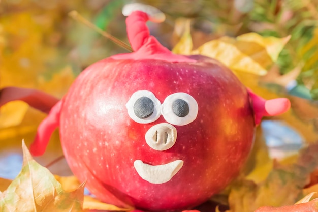 Photo children crafts pig from red apple and plasticine on yellow autumn leaves