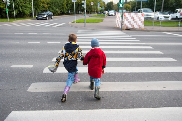 I bambini attraversano la strada attraverso un passaggio pedonale. strisce di strisce pedonali