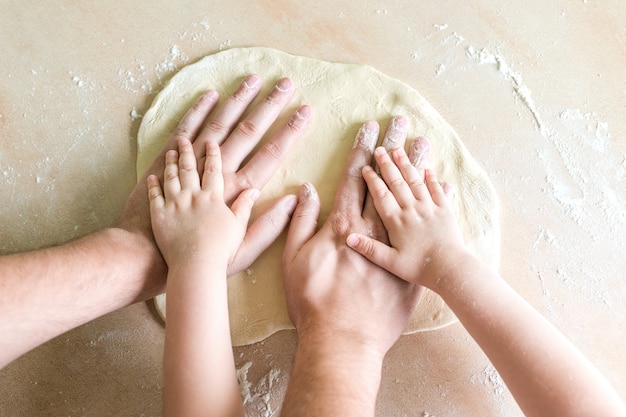 Children and dad hands on dough