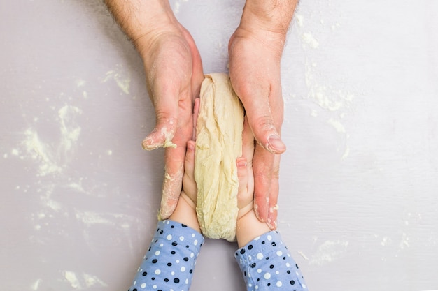 Children and dad hands make a dough