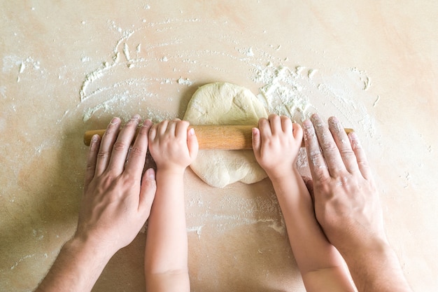 Children and dad hands rolled dough