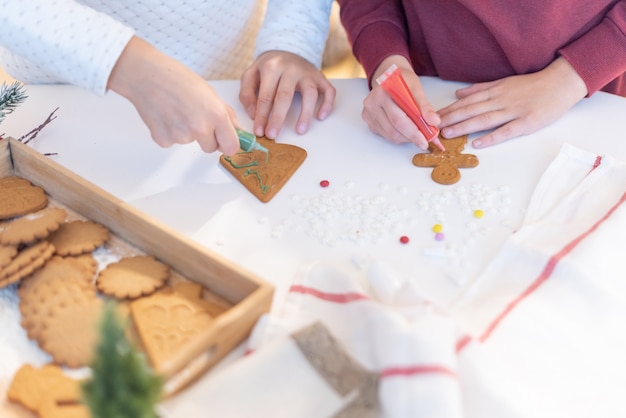 Foto i bambini decorano i biscotti di natale allo zenzero con le matite di zucchero