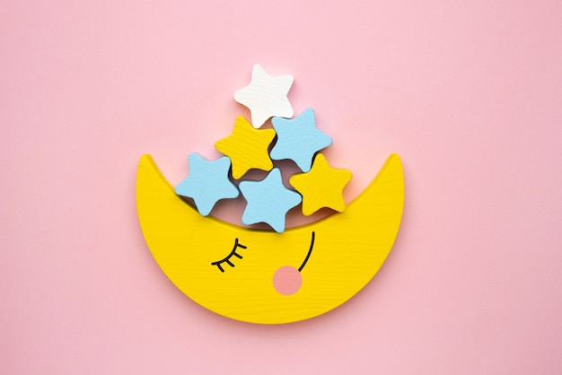 Children developmental toy for the development of motor skills, a crescent moon with stars balancer, on a pink background top view