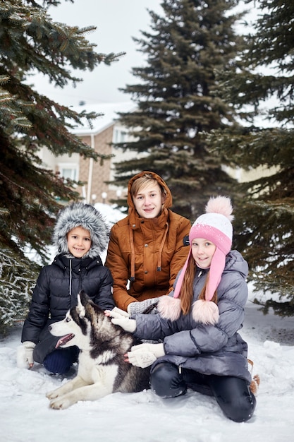 Children and a dog sit in the snow