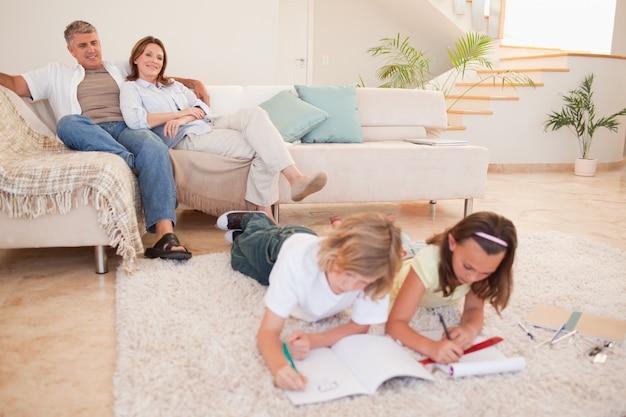 Children doing homework with parents behind them