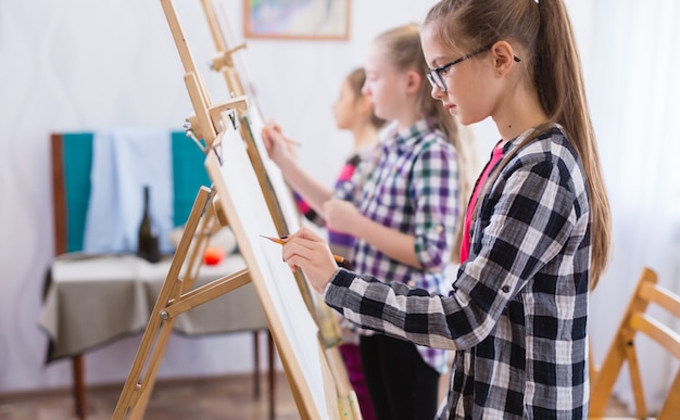 Children draw on an easel in art school.